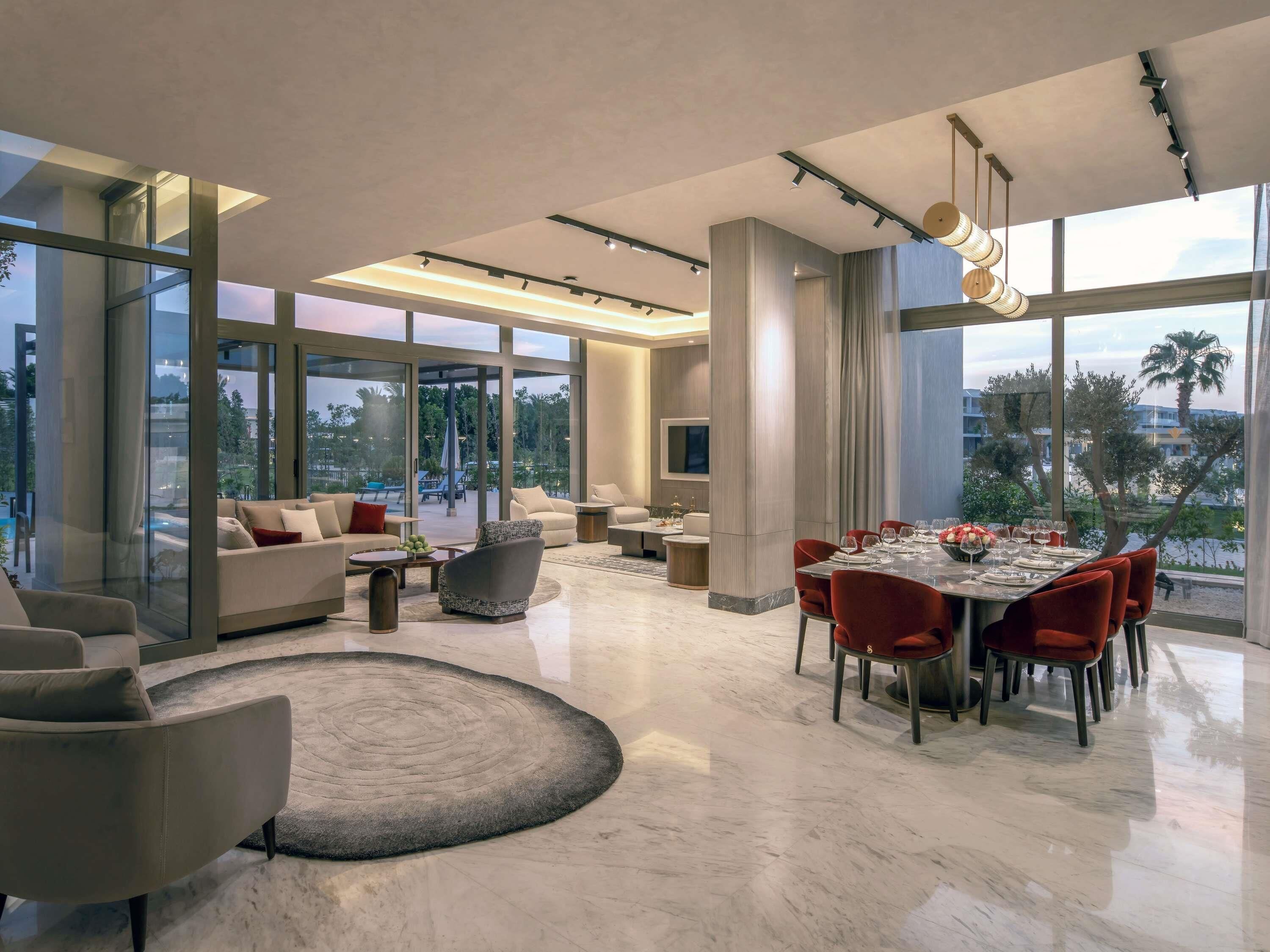 A modern interior with a dining area, sofas, and large windows.