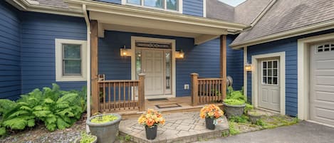 A residential house with a porch, a garage, and potted plants.