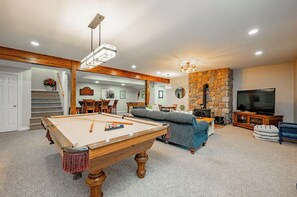 Una sala de estar con mesa de billar, chimenea y televisor.