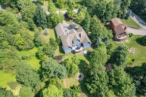 A large two-story house with a spacious deck and a hot tub. - New! Dog Friendly Lake Access Home w/ Hot Tub (Swanton)