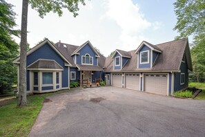 A two-story house with a front porch, a garage, and a driveway. - New! Dog Friendly Lake Access Home w/ Hot Tub (Swanton)