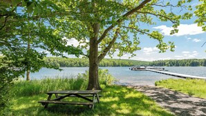 Un espacio para picnic frente al lago, con un banco y un muelle que se adentra en el agua.