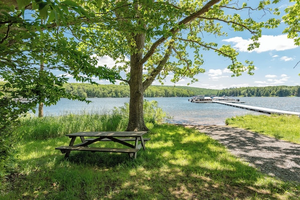 A lakeside picnic area with a bench and a dock extending into the water. - New! Dog Friendly Lake Access Home w/ Hot Tub (Swanton)
