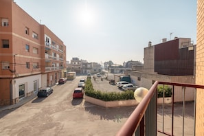 A parking lot with multiple cars, a building with a red facade, and a clear sky.