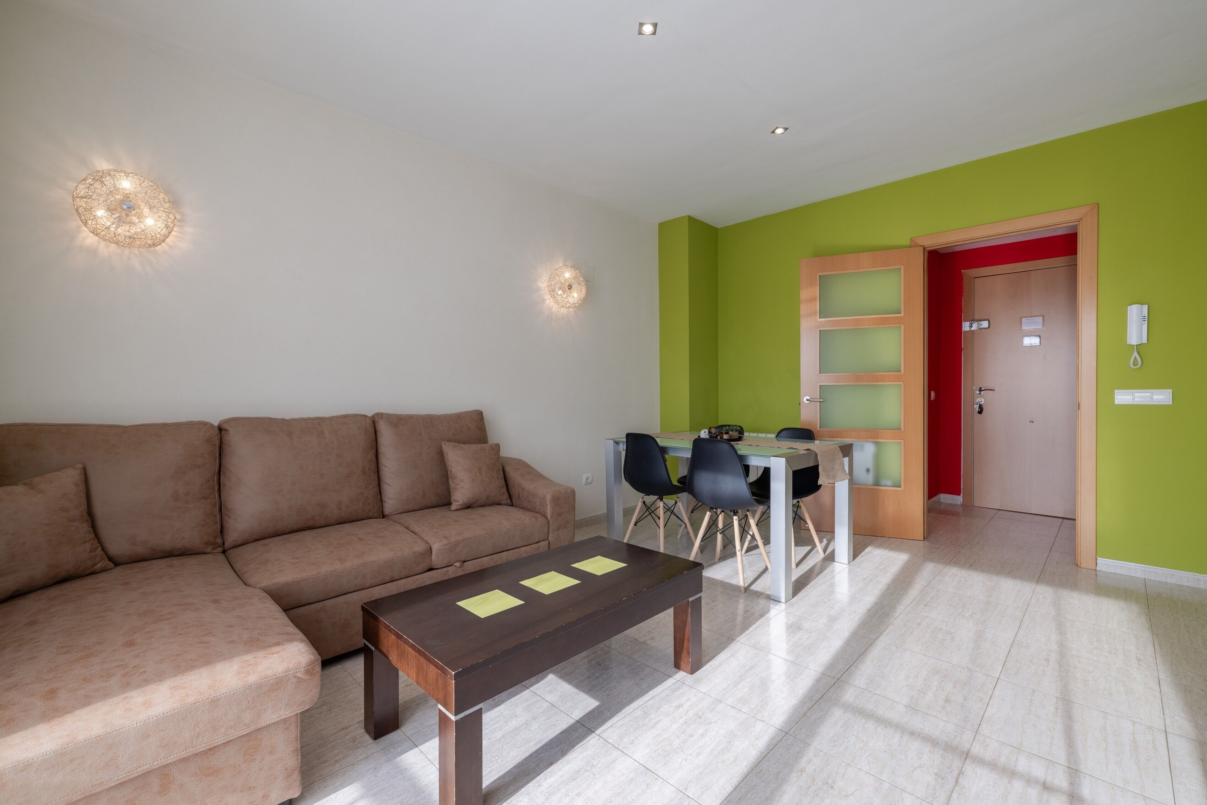 A living room with a brown sofa, a wooden coffee table, and a dining area with a table and chairs.