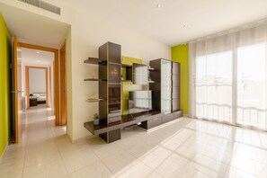 A modern living room with a large flat-screen TV, built-in shelves, and a sliding glass door to a balcony.