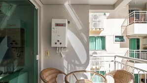A balcony with wicker chairs, a water heater, and a view of neighboring buildings. - Beautiful apt w/ Leisure Facilities Sbh0237 (Bombinhas)