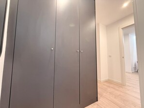 A modern, minimalist room with a grey wardrobe, light wooden flooring, and a plain white wall. - Discover a space designed for comfortable and stylish Madrid living in the heart of Chamberí, one of the city's most authentic and charming neighborhoods. (MADRID)