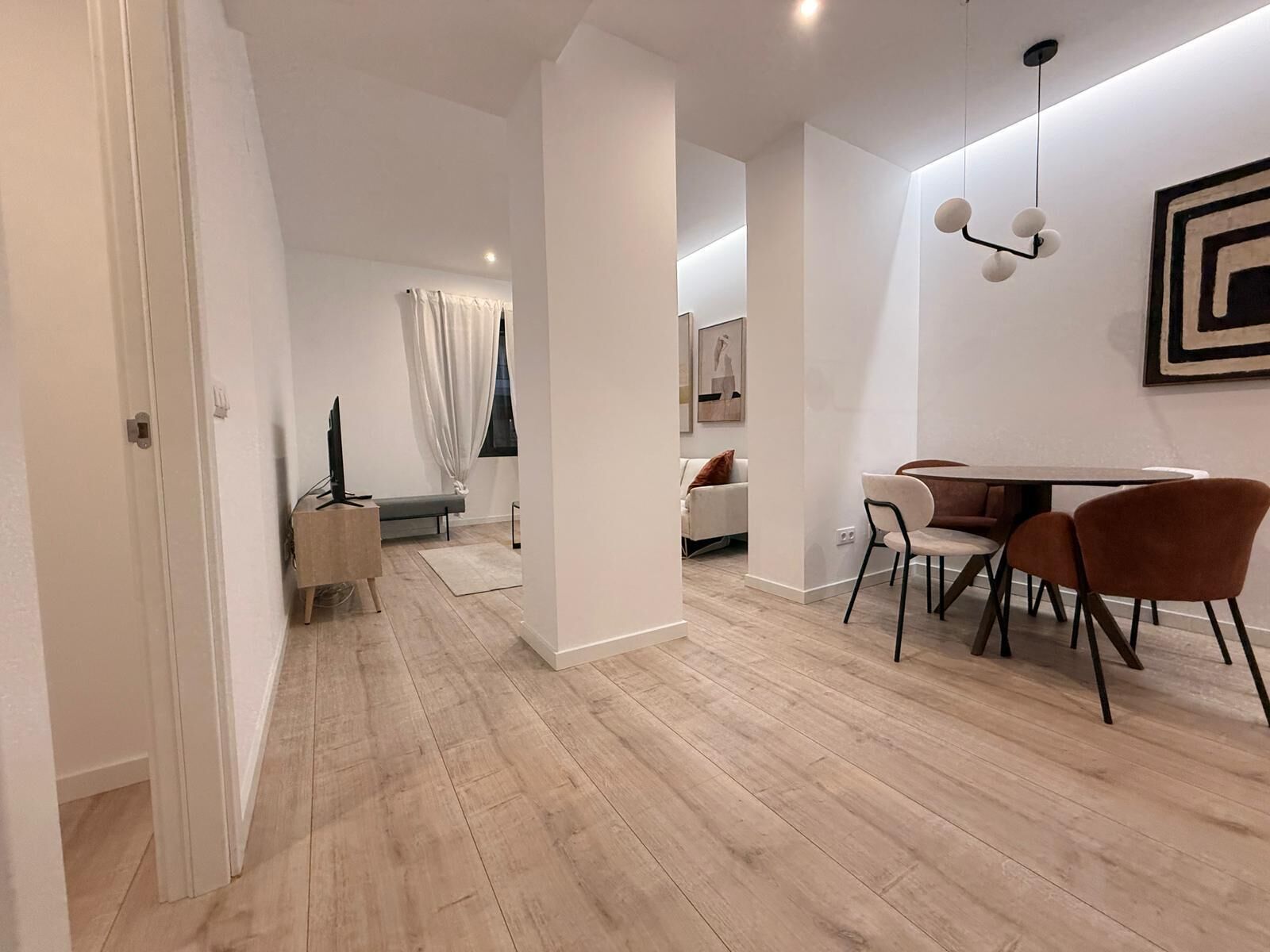 Un salon moderne avec un coin repas, un parquet en bois et un design minimaliste.