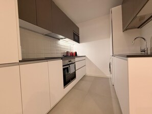 A modern kitchen with white cabinets, a stainless steel range hood, and a built-in oven. - Discover a space designed for comfortable and stylish Madrid living in the heart of Chamberí, one of the city's most authentic and charming neighborhoods. (MADRID)