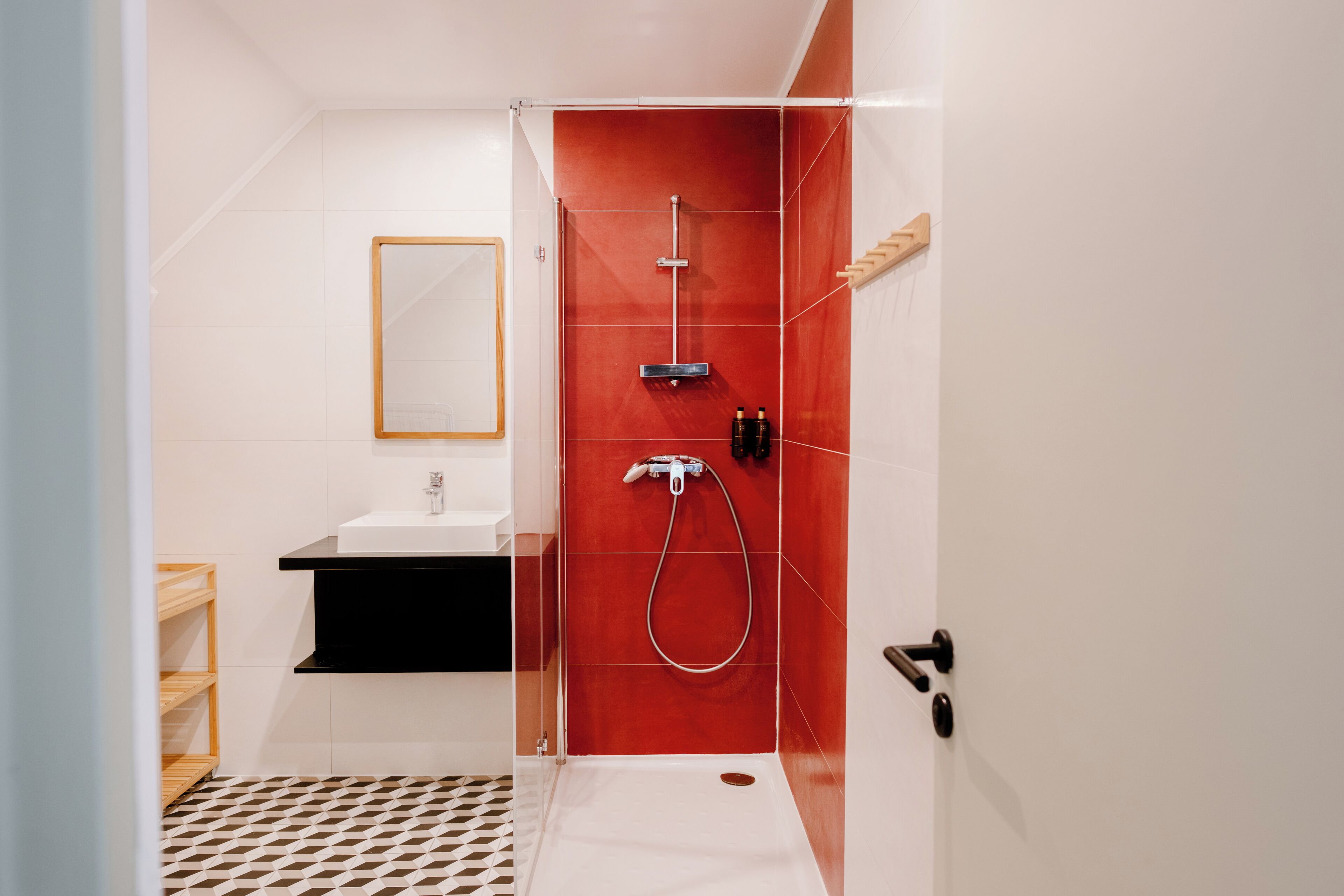 A modern bathroom with a glass-enclosed shower, a white sink, and a black countertop.