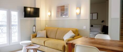 A modern living room with a sofa, a coffee table, and a dining table.