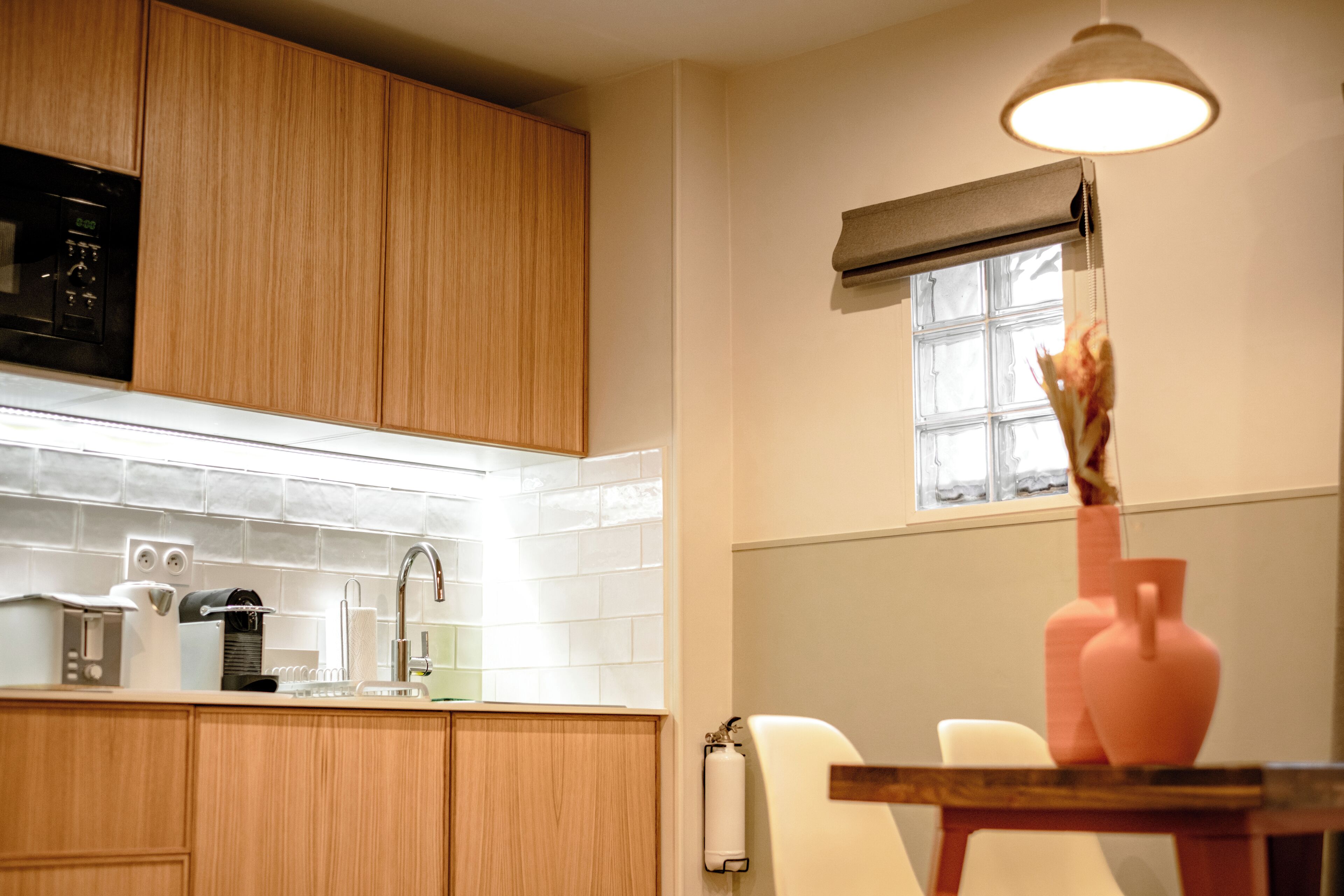 A kitchen with wooden cabinets, a sink, a coffee maker, and a vase on the table.