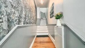 A hallway with a wooden floor, grey walls, and a textured wall on the left. - Comfortable 3 Bed Flat in King Cross (London)