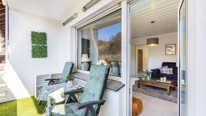 Un salon moderne avec une porte vitrée donnant sur un balcon, un canapé, une table basse et un petit tapis.