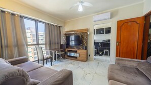 Ein Wohnzimmer mit Fernseher, Sofa und Essbereich.