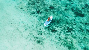 A person sitting on a paddleboard in clear turquoise water. - Kappa Senses Zanzibar (Pwani Mchangani)