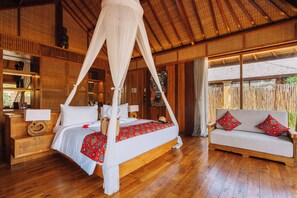 Une chambre dotée d’un lit à baldaquin, d’un canapé, d’un plancher en bois et d’un toit de chaume.