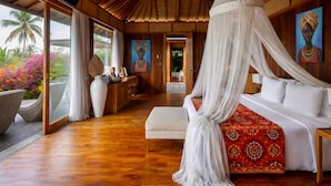 Un dormitorio con cama a dosel, suelo de madera, un escritorio con un florero y obras de arte en las paredes.