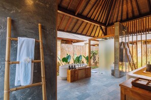 Une salle de bain dotée d’une grande baignoire, d’un meuble-lavabo en bois et d’un porte-serviettes en bambou.
