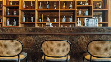 A bar area with a marble counter and three wicker chairs.