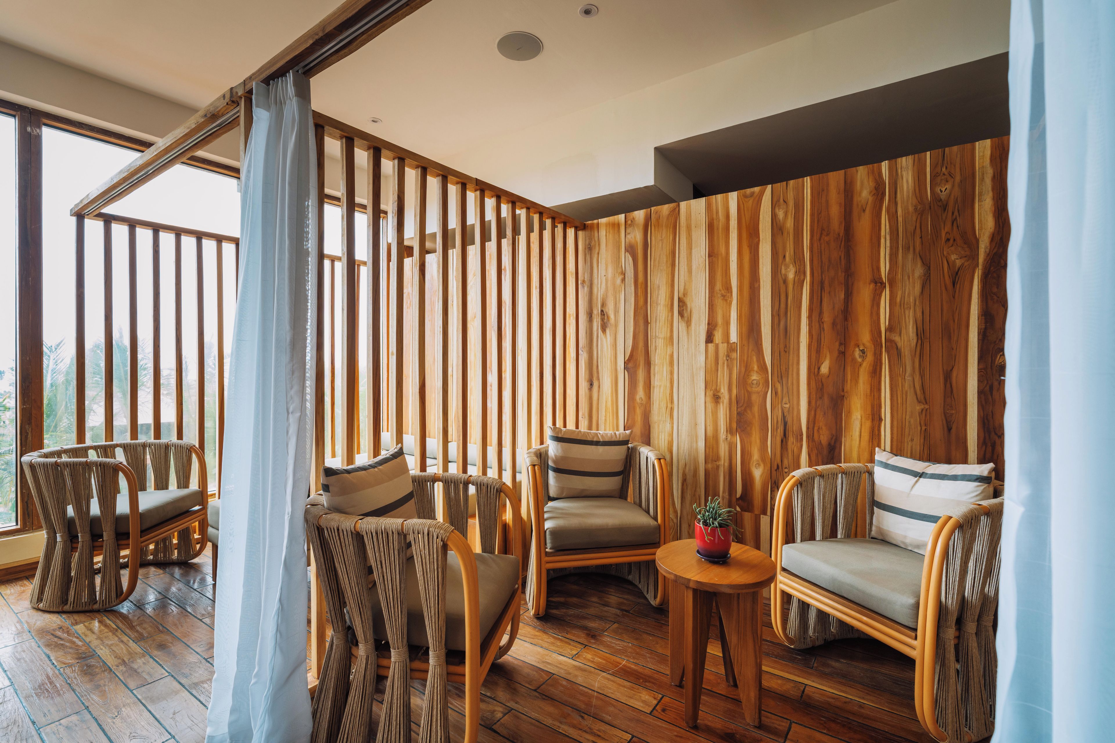 A room with wooden panel walls, a wooden floor, and wicker furniture.