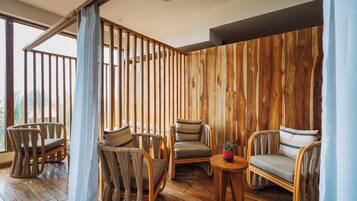 A room with wooden panel walls, a wooden floor, and wicker furniture.