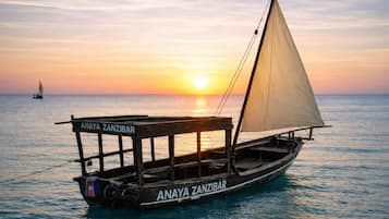 A traditional wooden boat named "Anaya Zanzibar" on calm waters during sunset.