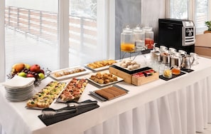 Ein reichhaltiges Buffet mit verschiedenen Speisen, einer Kaffeemaschine und einer Obstauslage.