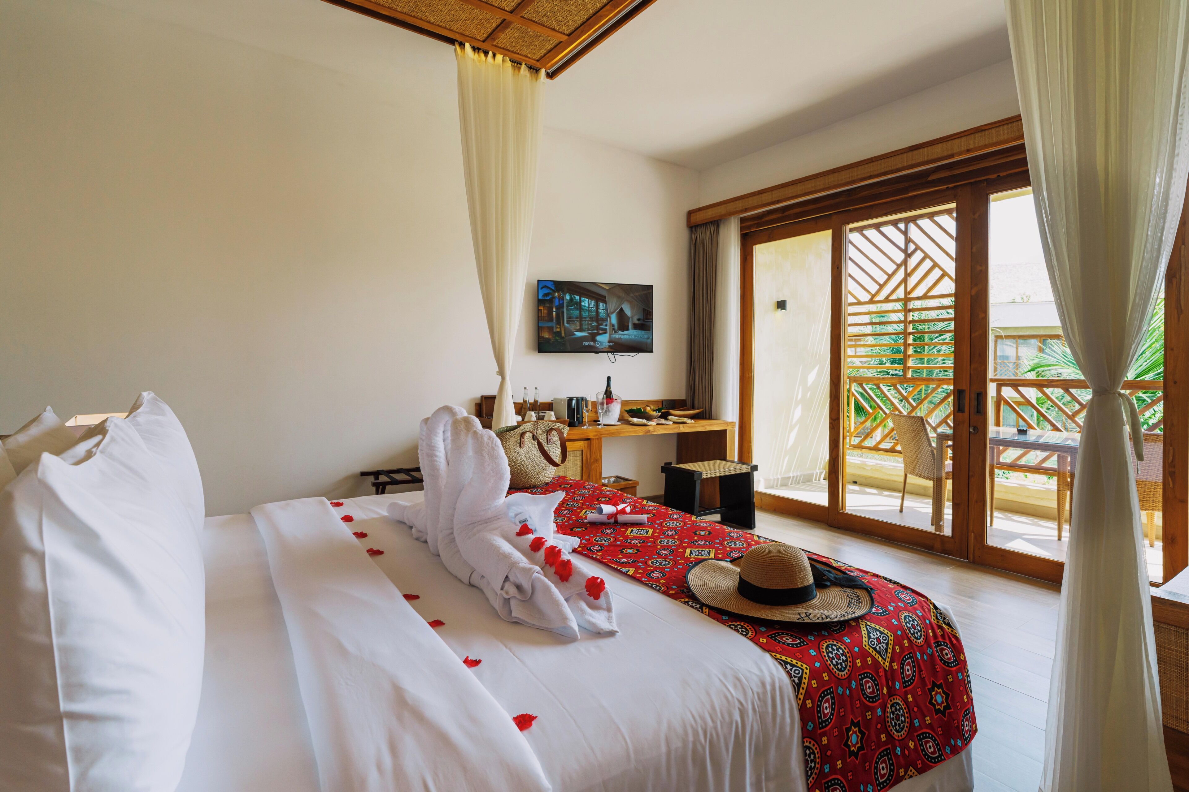 A hotel room with a bed, a desk, a TV, and a balcony with a view.