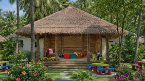 Une structure à toit de chaume, agrémentée d’équipements de jeux colorés et de bancs, située dans un jardin aux allures tropicales.