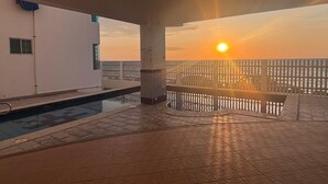 Zona de piscina en la azotea con vista al atardecer, una piscina y una baranda.