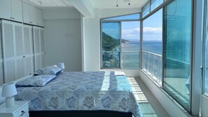 Un dormitorio con una cama grande, ventilador de techo y balcón con vista al mar.