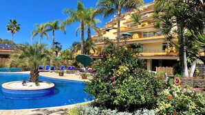 A resort with a swimming pool surrounded by palm trees and lounge chairs.