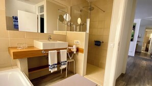A modern bathroom with a sink, mirror, towel rack, and shower area.