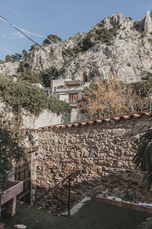 Un muro in pietra, una panchina di legno e un edificio con balconi.