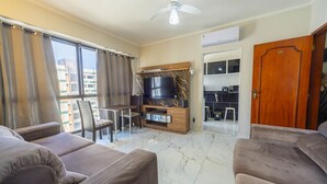 Una sala de estar con televisor, sofá y comedor.