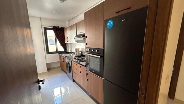 A modern kitchen with wooden cabinets, a stainless steel refrigerator, and a gas stove. - Burj Malaak apartment in a private residence with swimming pool (Marrakech)