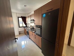A modern kitchen with wooden cabinets, a stainless steel refrigerator, and a gas stove. - Burj Malaak apartment in a private residence with swimming pool (Marrakech)