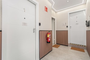A corridor with doors, a fire extinguisher, and a doormat. - Dobo Madrid Siena (Madrid)