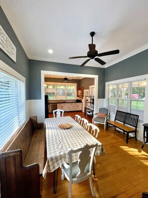 A dining area with a checkered table, white chairs, and a wooden bench. - Good Ol' Country Farmhouse (Moncure)