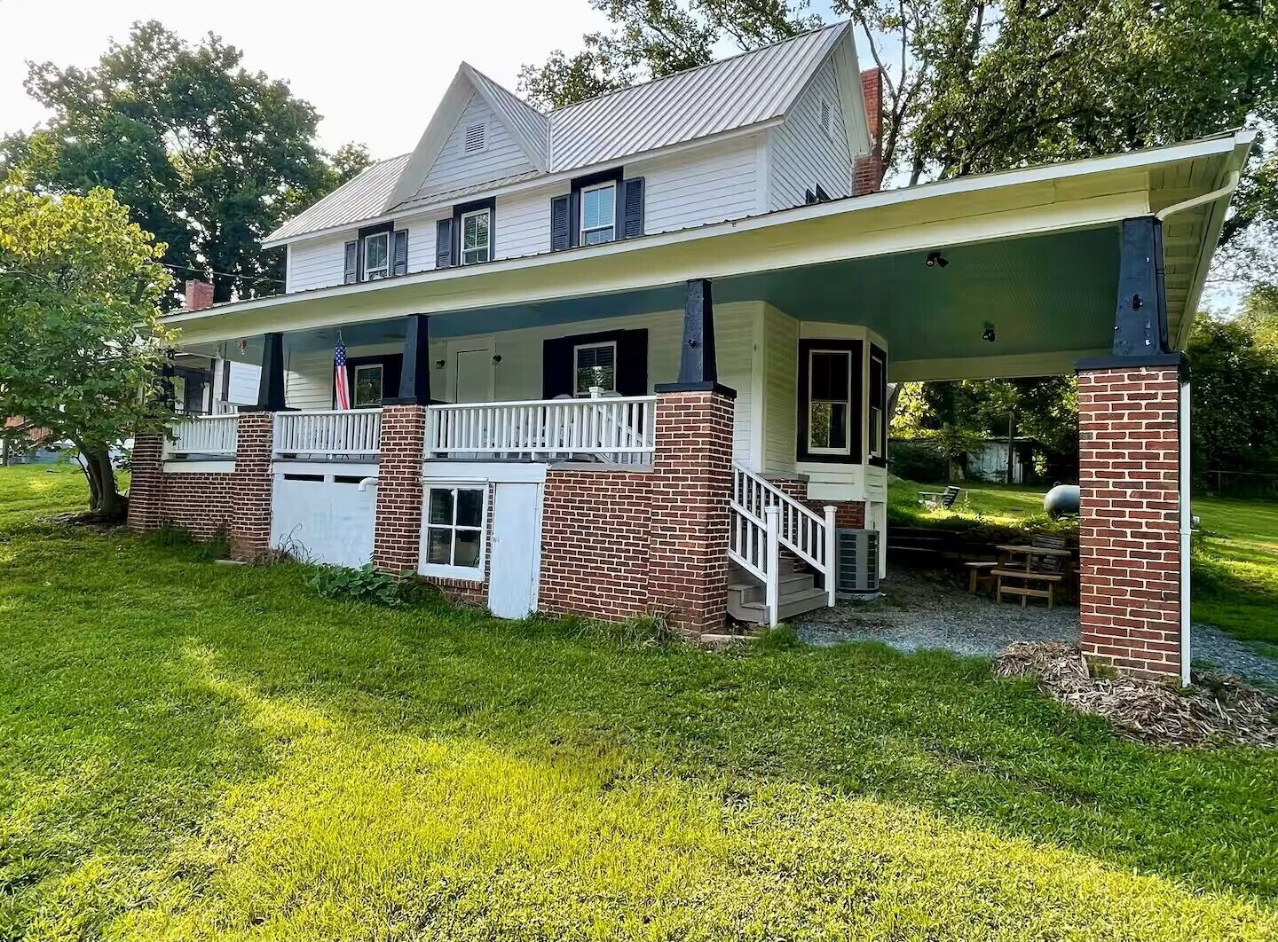 A two-story house with a covered porch, brick foundation, and a small front yard.