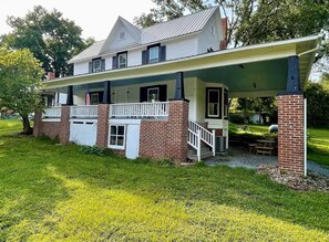 A two-story house with a covered porch, brick foundation, and a small front yard. - Good Ol' Country Farmhouse (Moncure)