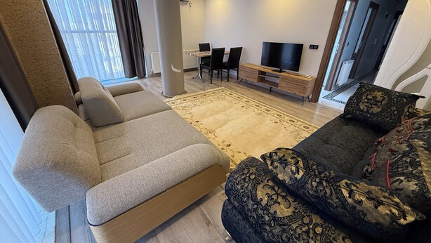 Un salon moderne comprenant un canapé, un fauteuil à motifs, un téléviseur et un coin repas.