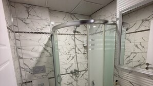 Une salle de bain avec une douche à parois de verre, des toilettes, un lavabo et un miroir.