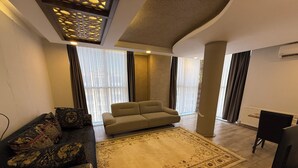 Un salon avec un canapé, un tapis à motifs et un téléviseur.