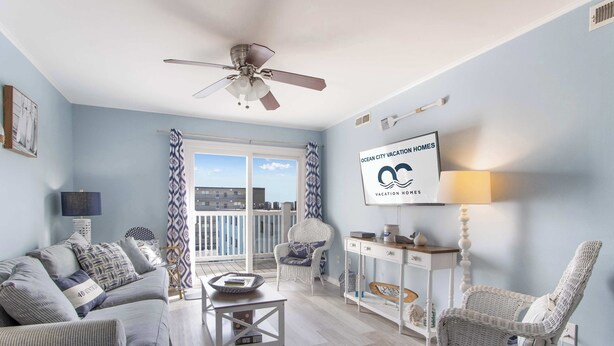 Un salón amplio con balcón, ventilador de techo y un letrero de Ocean City Vacation Homes.