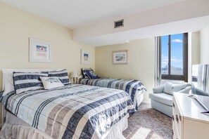 A bedroom with two beds, a desk, and a window with a view. - Braemar Towers S 1406 (Ocean City)
