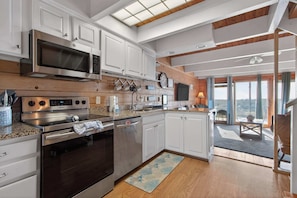 A modern kitchen with stainless steel appliances, white cabinetry, and a wooden ceiling. - Beach Place North 2 (Ocean City)