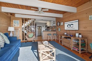 A wooden interior with a sofa, a table, a kitchen area, and a sign for Ocean City Vacation Homes. - Beach Place North 2 (Ocean City)